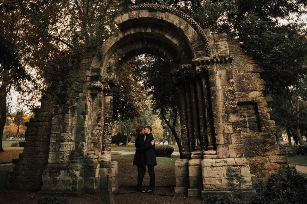 Gay couple kissing under an ancient Roman arch